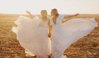 two brides at golden hour fluffing wedding gowns up in air for the perfect shot