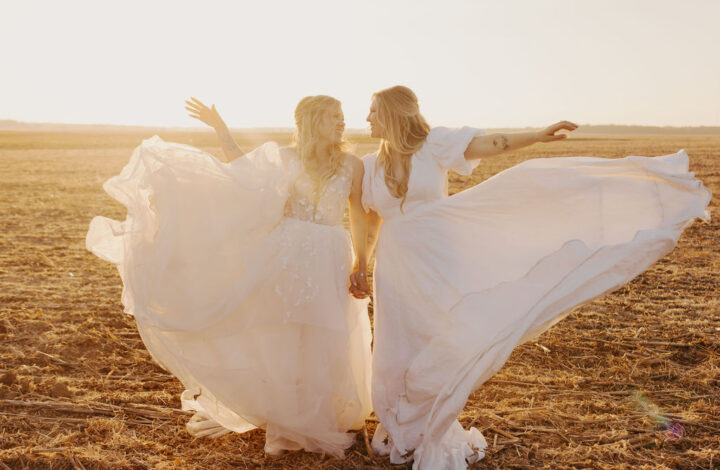 two brides at golden hour fluffing wedding gowns up in air for the perfect shot
