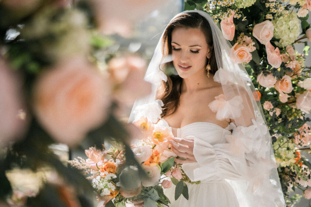 stunning bridal portrait of bride surrounded by summer-inspired wedding flowers with ethereal gow