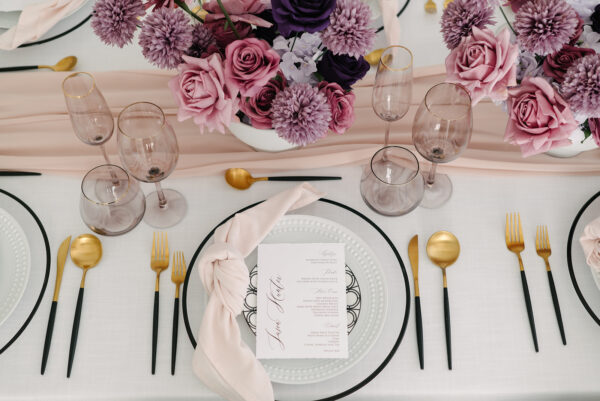 stunning wedding table with black and gold silverware and lavender and dark purple flowers at styled shoot