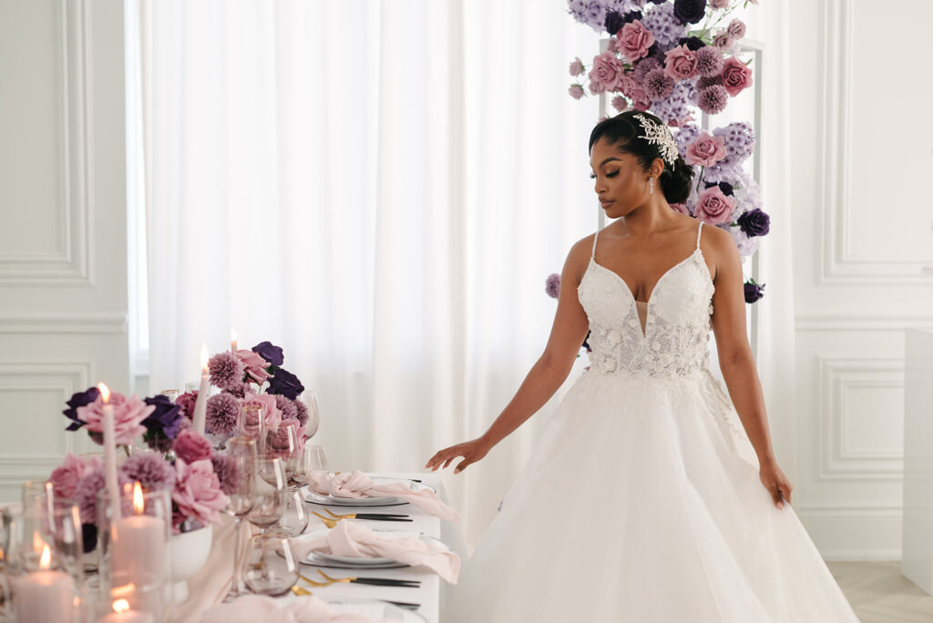 beautiful bride in strapless gown poses for portrai next to stunning tablescape wtih lavender decor at styled shoot