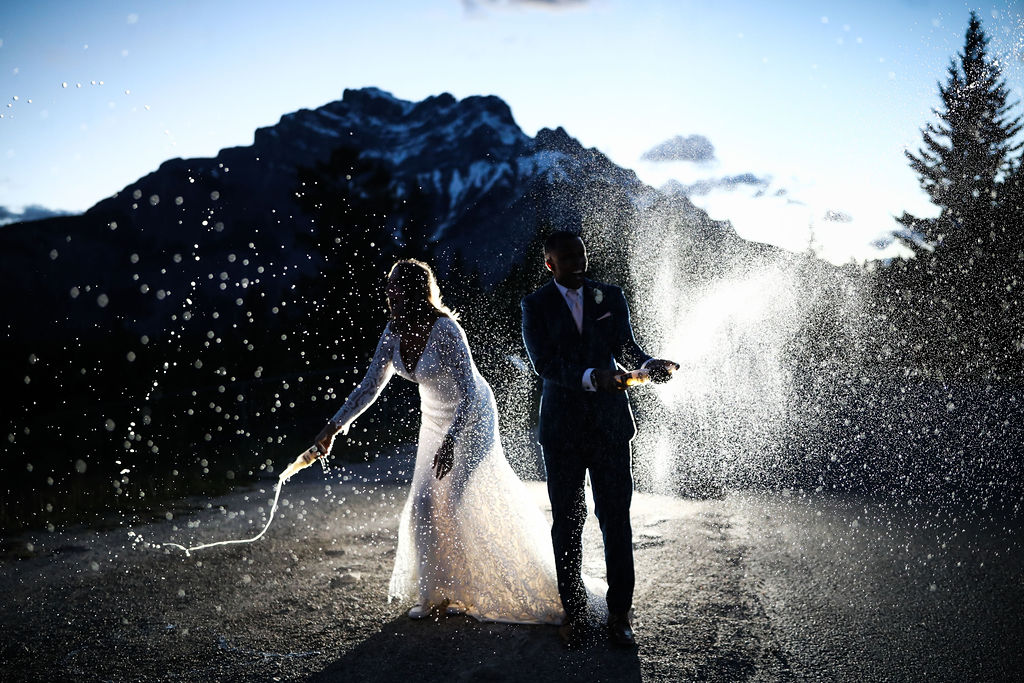 Incredible image of bride and groom spraying champagne during the perfect elopement in Banff Canada