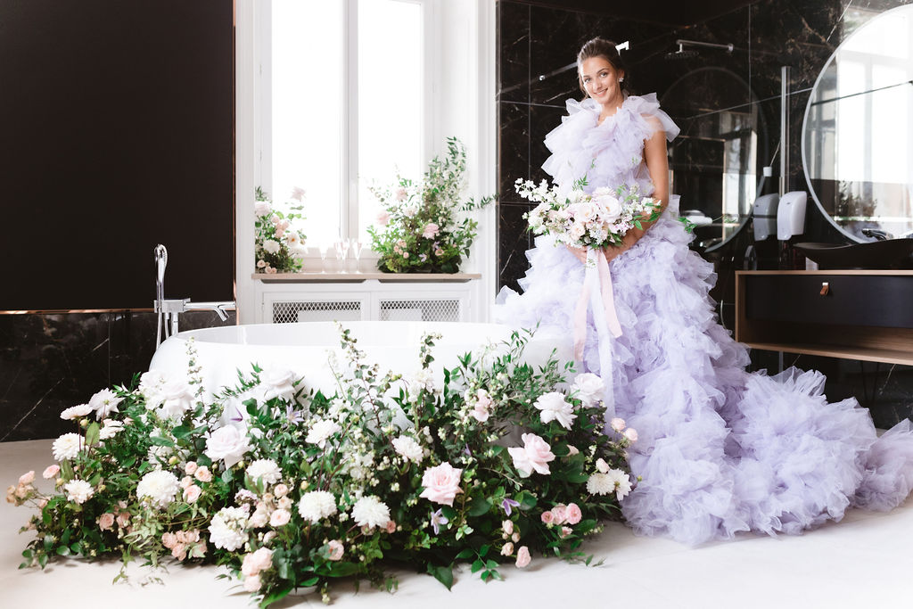 beautiful bride wearing a soft lavender gown with ruffles with large floral installation made by talented wedding florist @laeCCaclement_floraldesigner