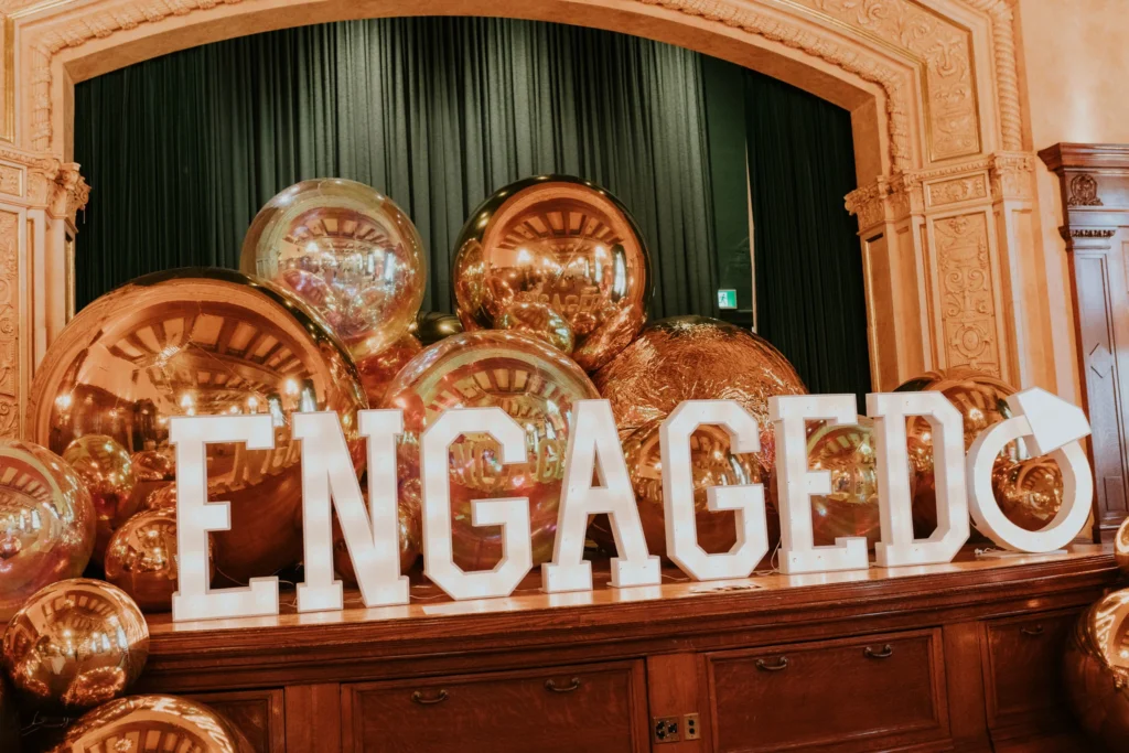 wedding planning timeline picture of engagement location with big metallic balls and illuminated engaged sign