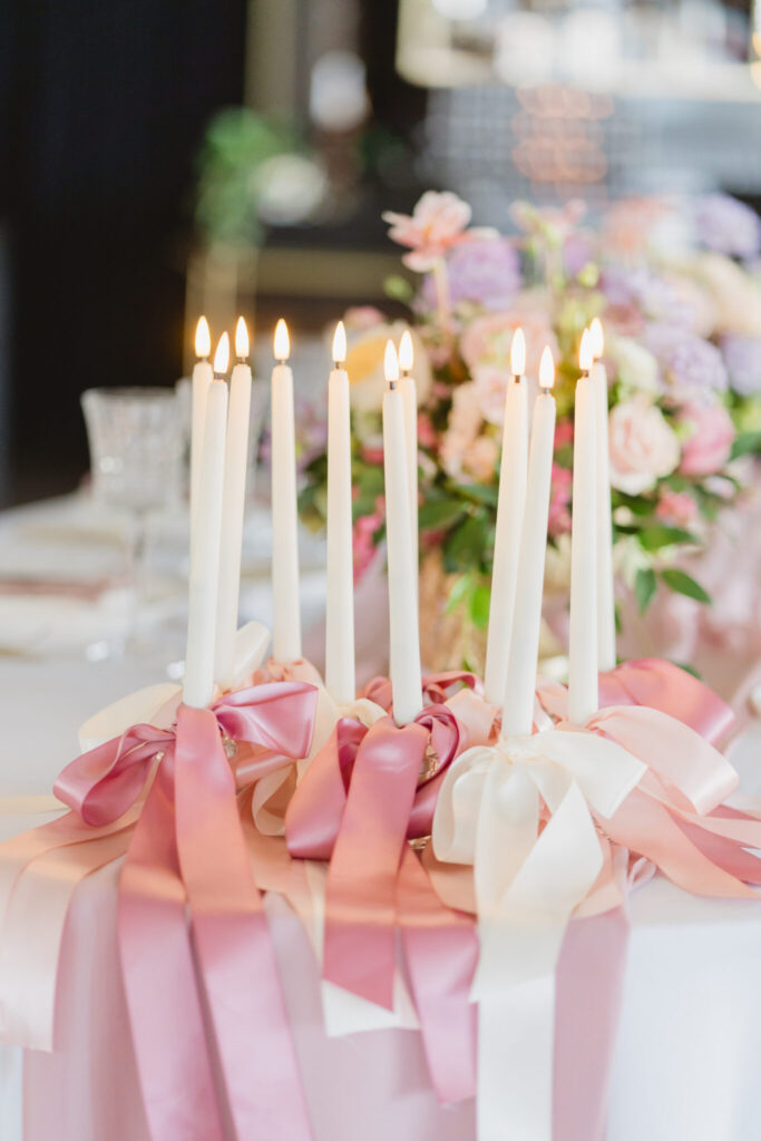 romantic candles with ribbons and bows on wedding table during styled shoot