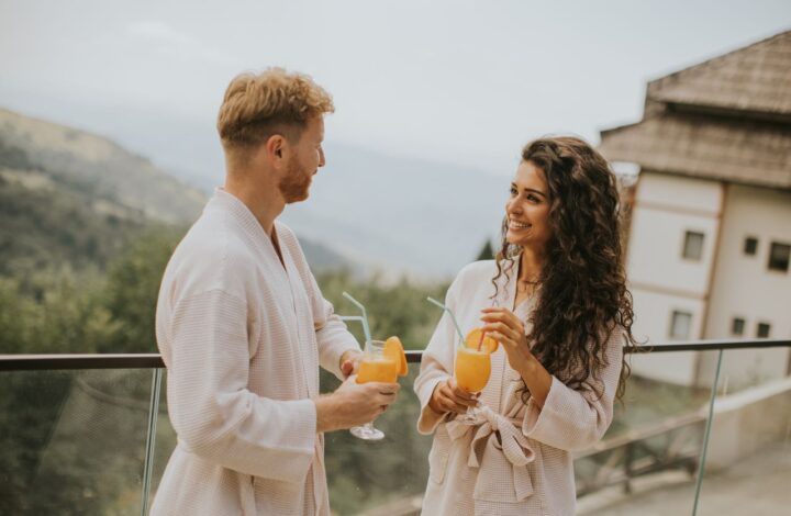 newlywed couple stand on terrace wearing matching bathrobes from wedding gifts