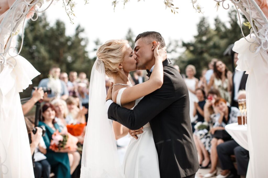 bride and a groom are kissing in front of the wedding guest plus-one wedding officiant