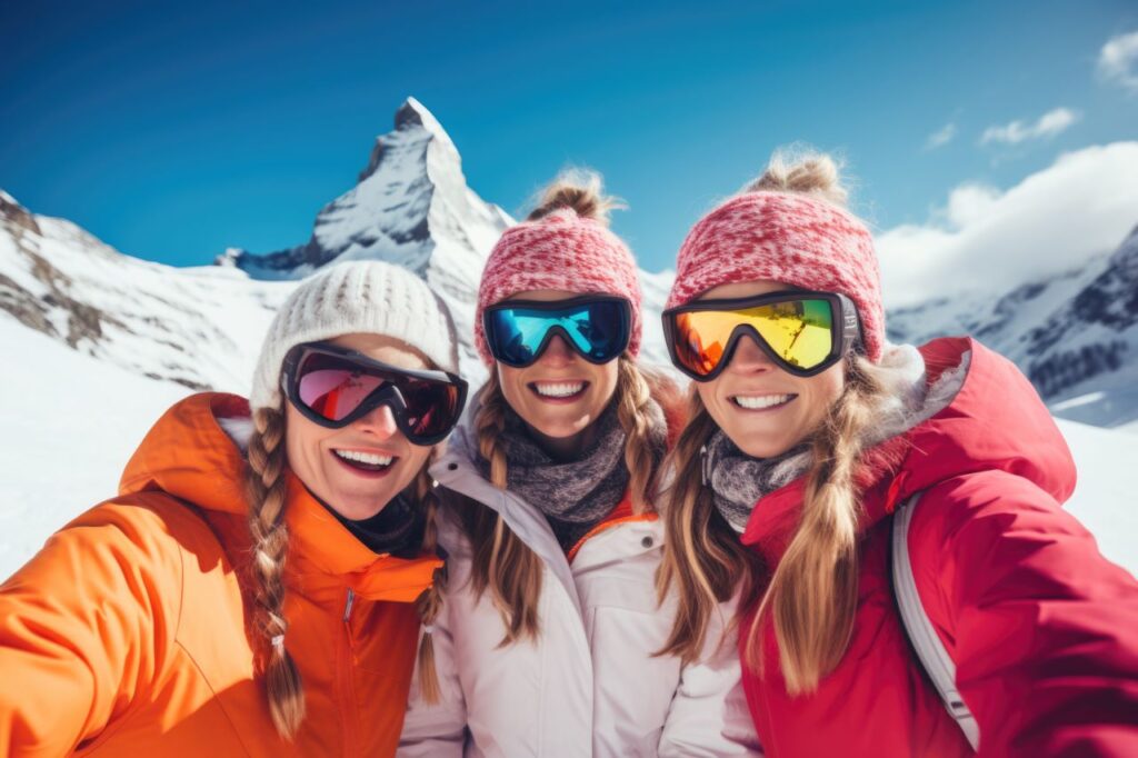 group of bachelorettes pose on snowy mountain in ski suits and goggles winter bachelorete getaway