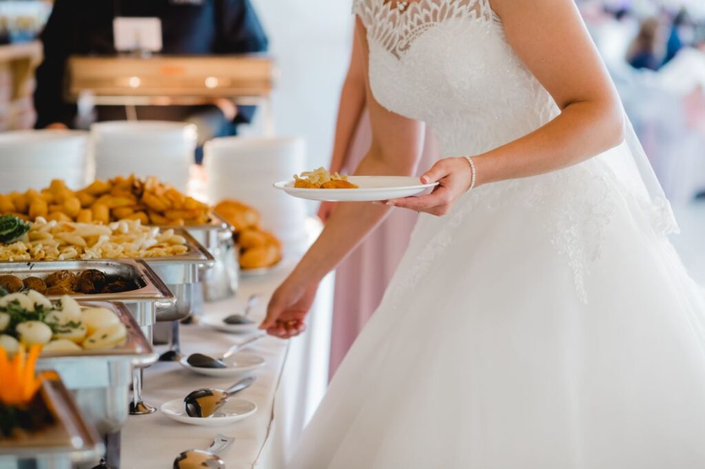 bride getting food from wedding caterer buffet table