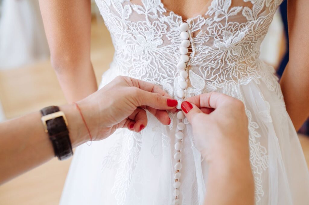 wedding dress mishaps woman fixes buttons on back of dress