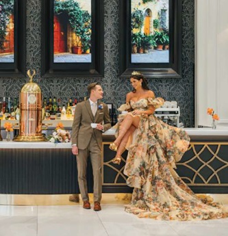 bride in floral off the shoulder wedding dress sitting on bar during destination wedding styled editorial