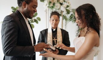 wedding officiant with bride and groom putting rings on