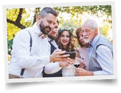 bride and groom looking at photos on phone with guests during destination wedding