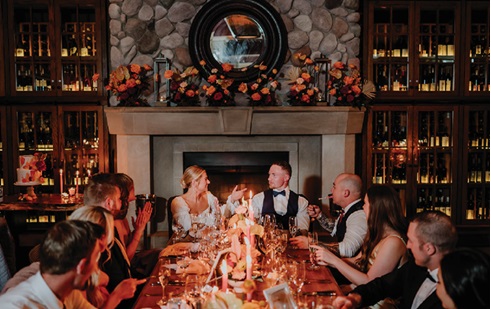 fun portrait at micro-matrimony event with bride and groom toasting with small group of guests at wedding reception table