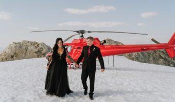 stunning snowy wedding portrait of bride and groom in front of red helicopter