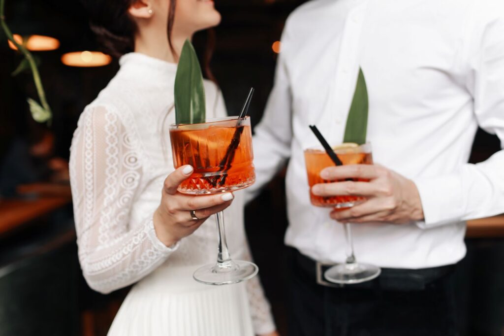 bride and groom gaze at each other holding tropical signature wedding drink outdated wedding trends
