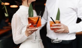 bride and groom gaze at each other holding tropical signature wedding drink outdated wedding trends