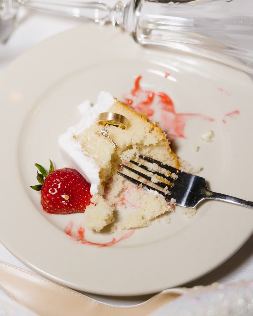 half eaten cake on plate with wedding rings - 2025 wedding photography trends