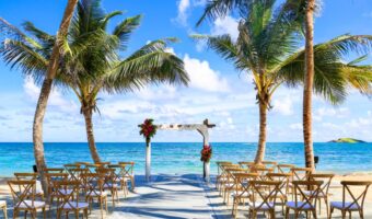 A beach wedding ceremony setup featuring an altar, chairs, and floral decorations with the ocean in the background