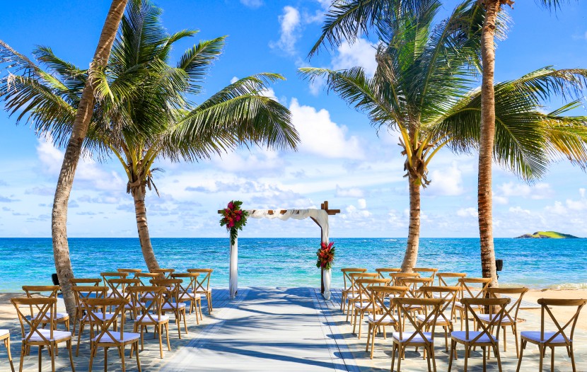 A beach wedding ceremony setup featuring an altar, chairs, and floral decorations with the ocean in the background