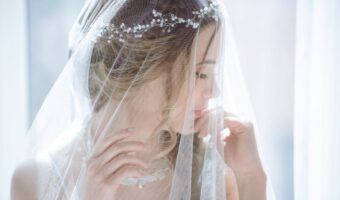 bride poses for demure portrait wearing wedding veil and vine headband