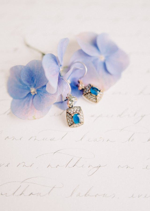 romantic handwritten love letter with blue flowers on it and blue gemstone earrings that bride choose wedding jewellery