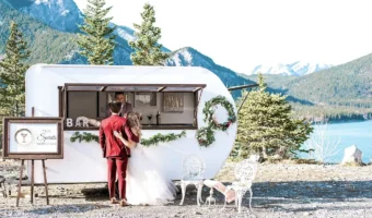 bride and groom standing at True Spirits mobile bar with Canada landscape in background