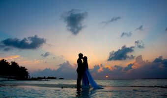 bride and groom stand on beach for blue hour wedding photography