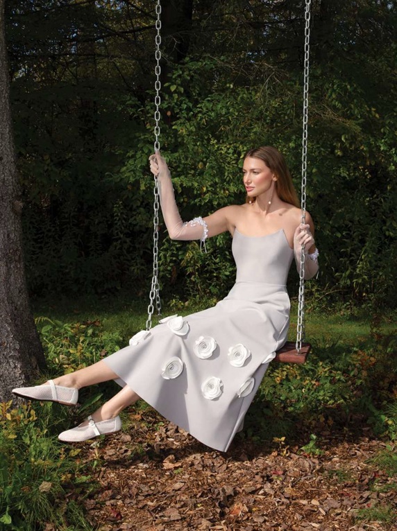 bride swinging in forest with wedding dress with 3 dimensional flowers on skirt for real bridal fashion moment