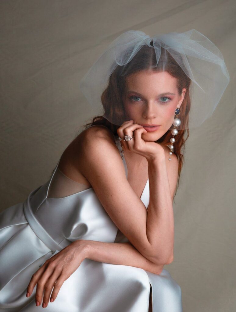 Model wearing birdcage veil and dramatic chandelier earrings with large balls