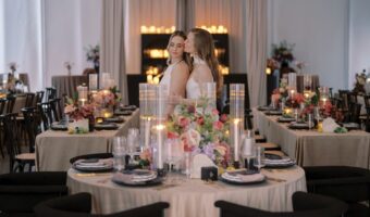 two brides pose for picture next to wedding tables during styled wedding shoot