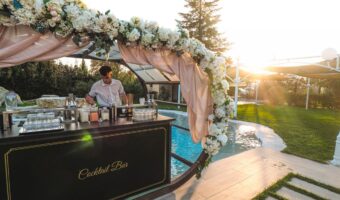 young bartender standing at open bar at weddings decorated with beautiful floral garland