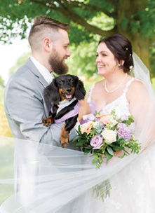 outdoor wedding portrait of bride and groom with puppy on wedding day
