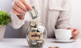 woman putting into wedding budget jar with holding coffee cup
