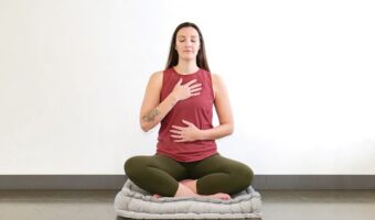 woman sitting on mat doing yoga pose while meditating and practicing self care
