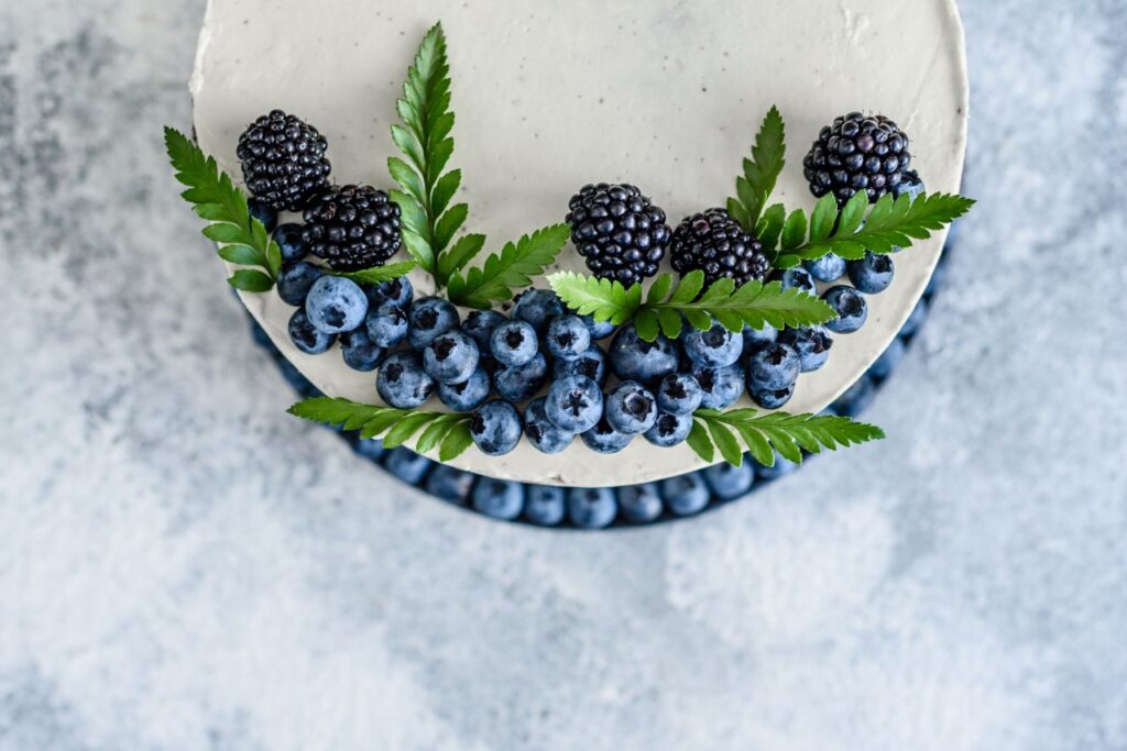 ivory and blue wedding cake with blackberries, blueberries and greenery fruit is a 2026 wedding cake trends