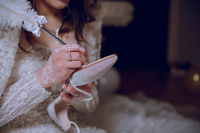 bride writing on bottom of shoes with feather pen wearing wedding dress for getting-ready photos