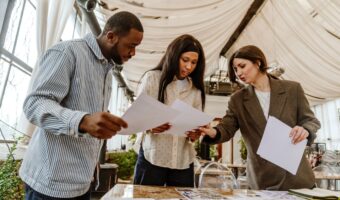 groom and bride meet with wedding planner to discuss sustainable wedding in venue with drapery on ceiling one of the benefits of a wedding planner