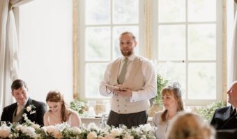 best man standing at head table giving toast after figuring out the wedding speech order