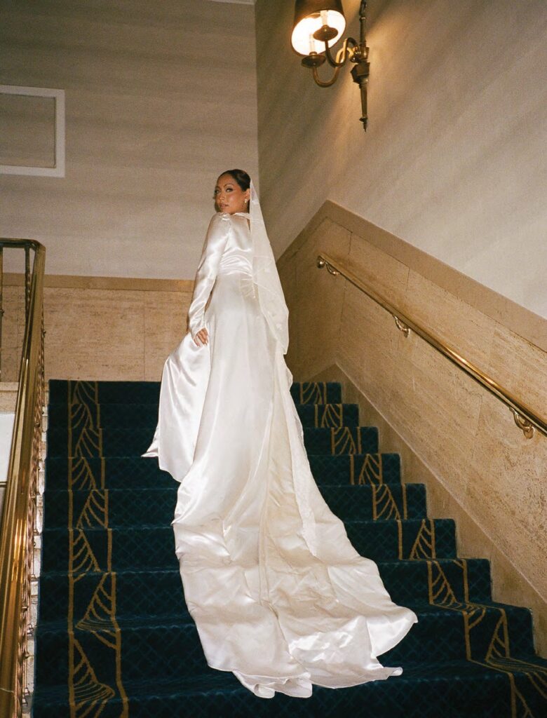vintage appeal bride posing on staircase wearing long sleeve silk wedding dresses