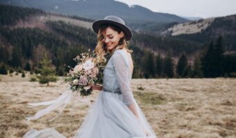 bride wearing wedding veil alternatives bridal hat in field with mountain background