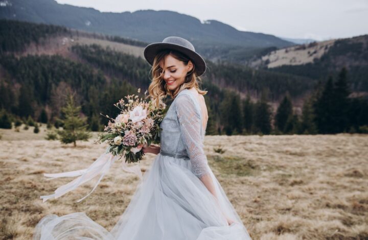 bride wearing wedding veil alternatives bridal hat in field with mountain background
