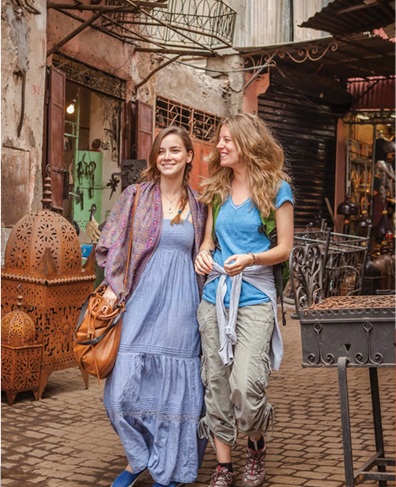 two women walking on old cobblestone street in Europe on honeymoon doing community tourism