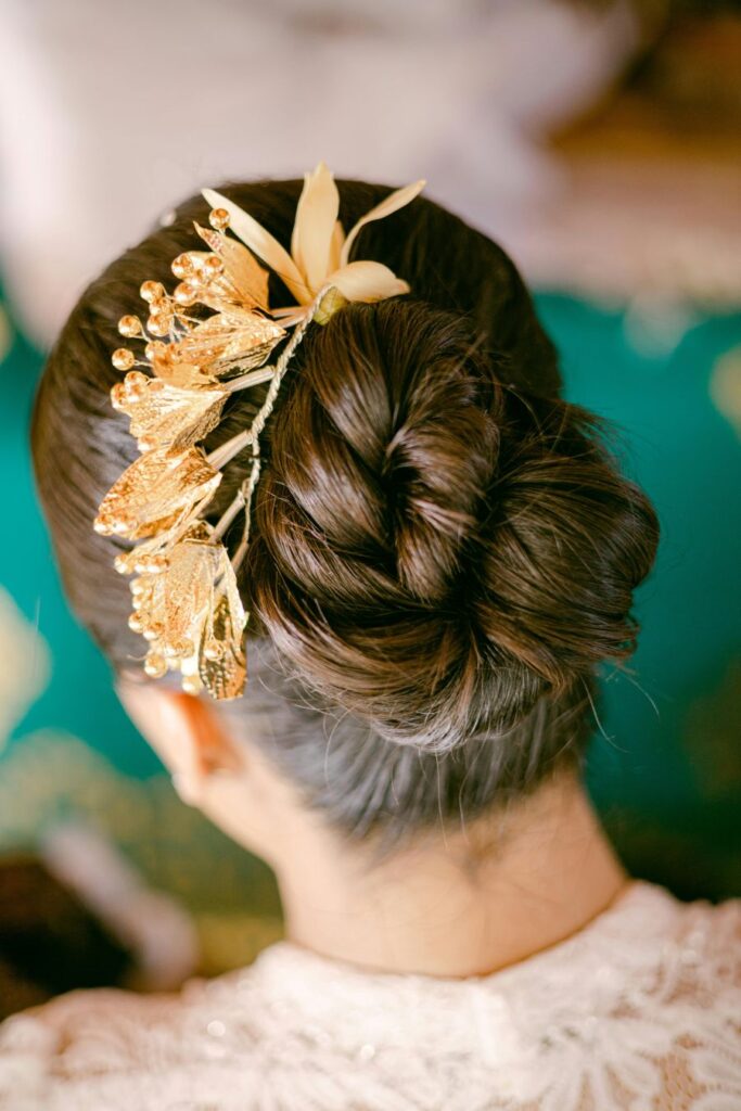 editorial portrait of back of brides hair romantic updo with large gold leaf accessory