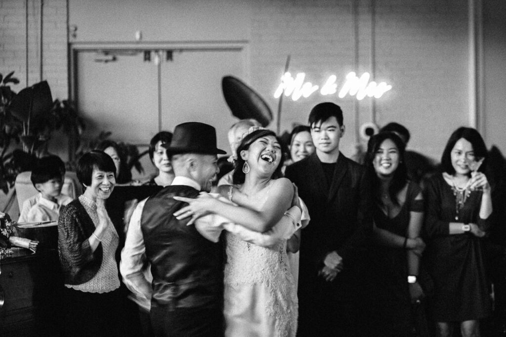 black and white portrait of bride and groom dancing and laughing film-style wedding photography by Loving Care Photography