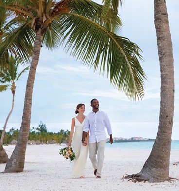 bride and groom walking on beach after destination wedding