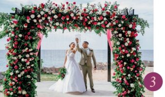 bride and groom pose under tropical wedding arch on beach