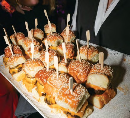 Tray of sesame-seed mini sliders on skewers ready for guests at a party.