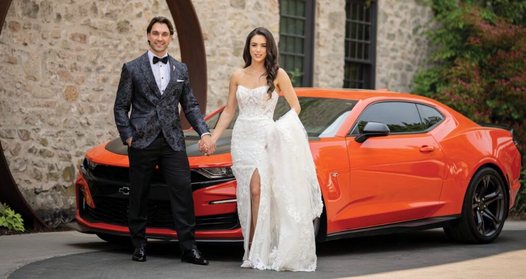 bride and groom pose with red sportscar at Elora Mill Hotel