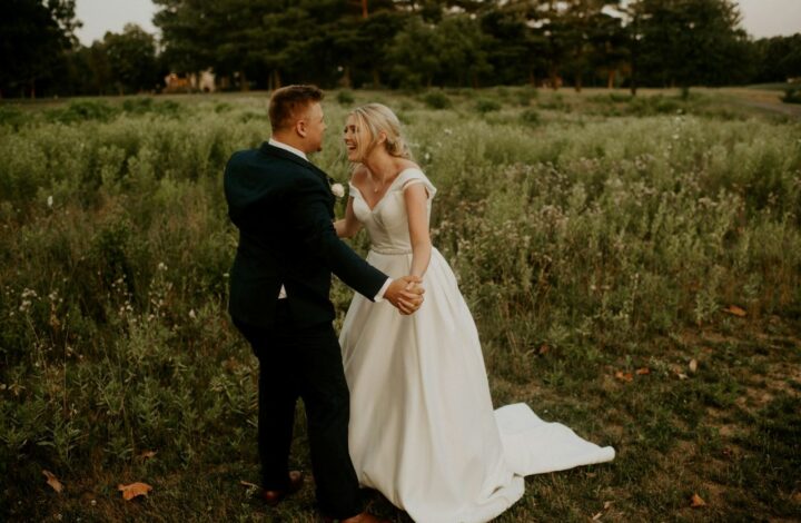 bride and groom laugh while holding hands in a field after talking about wedding planning mistakes